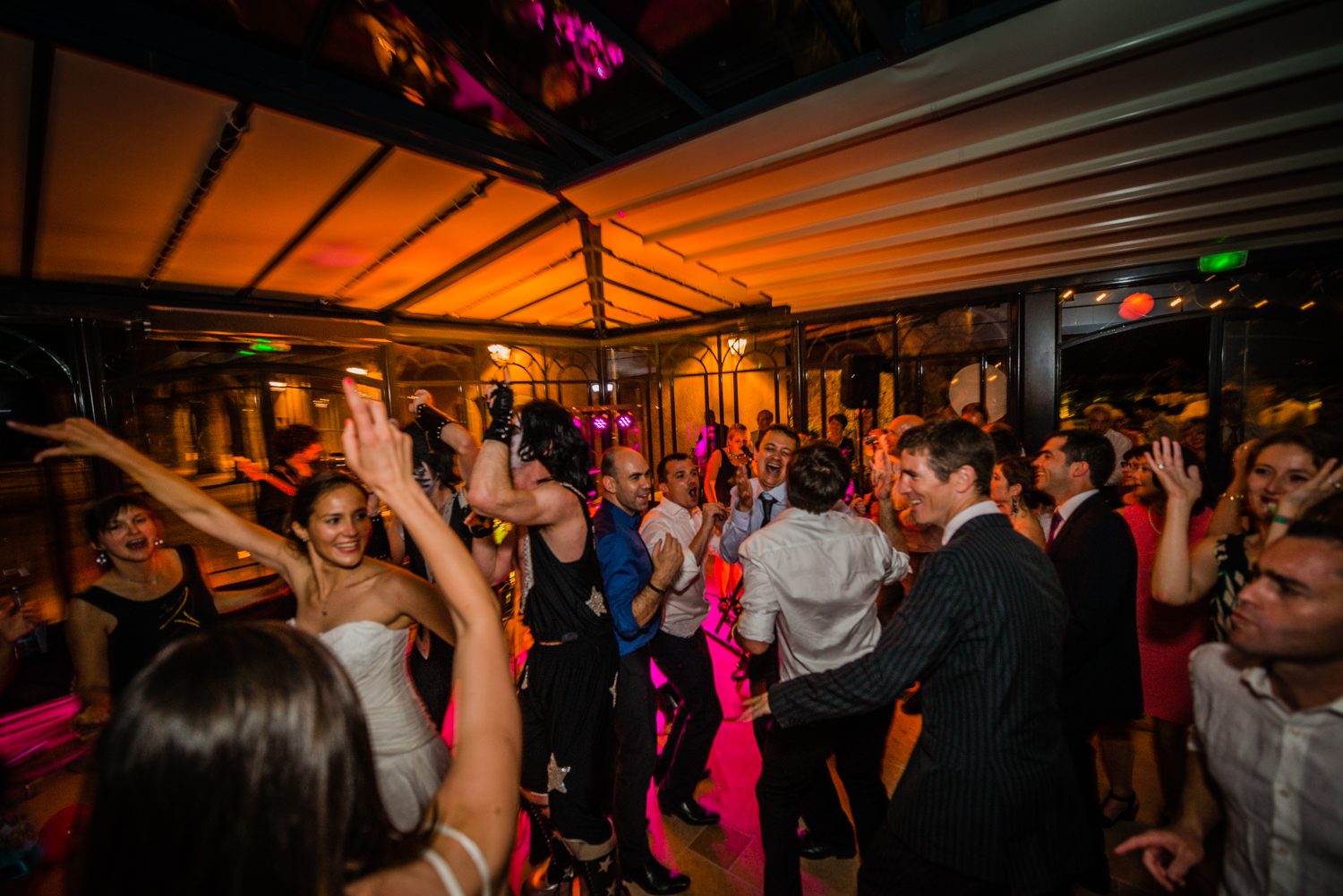 Piste de danse pleine, la mariée bras levés, pendant la soirée d'un mariage
